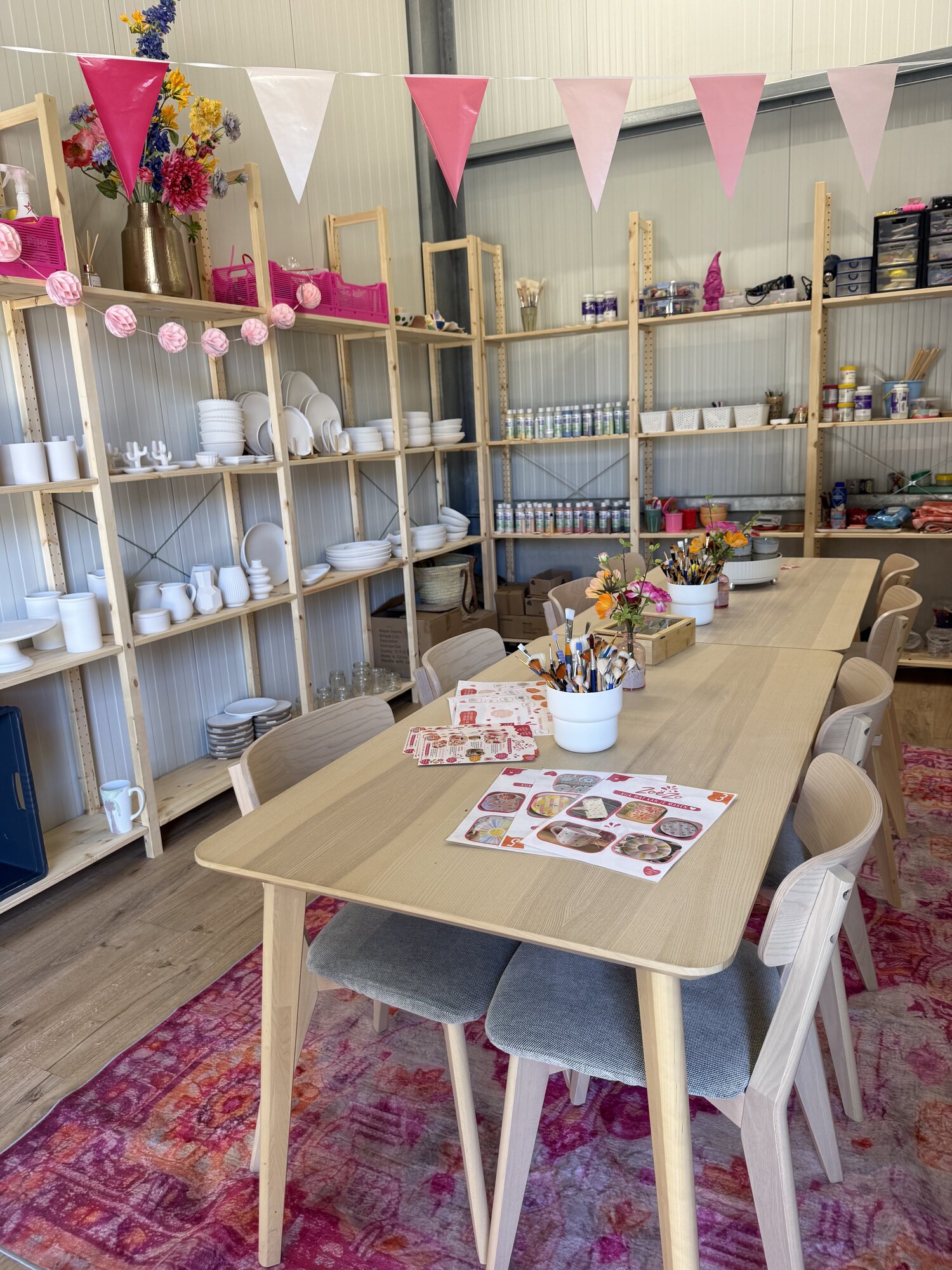 Overzicht van het creatieve atelier van ZoëZo Creatief in Odijk met een lange houten werktafel en kasten vol keramiek