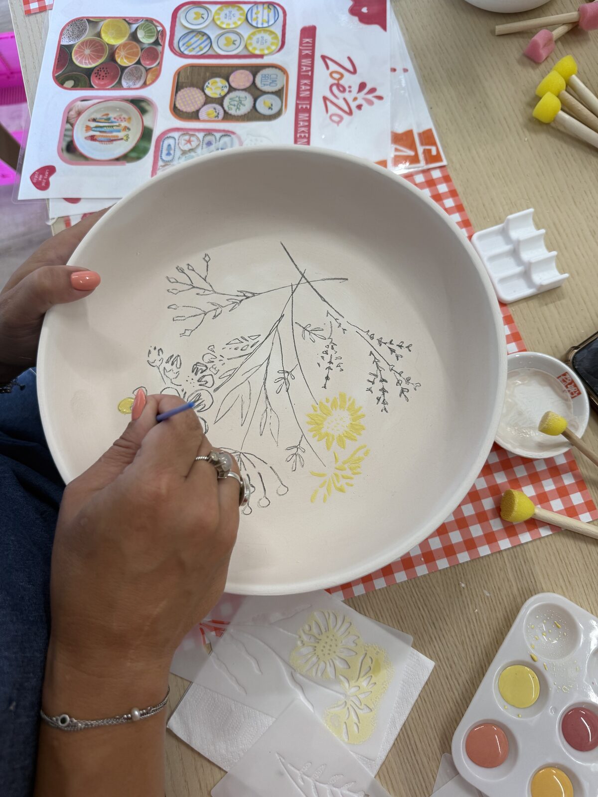 Vrouw schildert een botanisch bloemenpatroon op een keramieken bord tijdens een workshop in Odijk