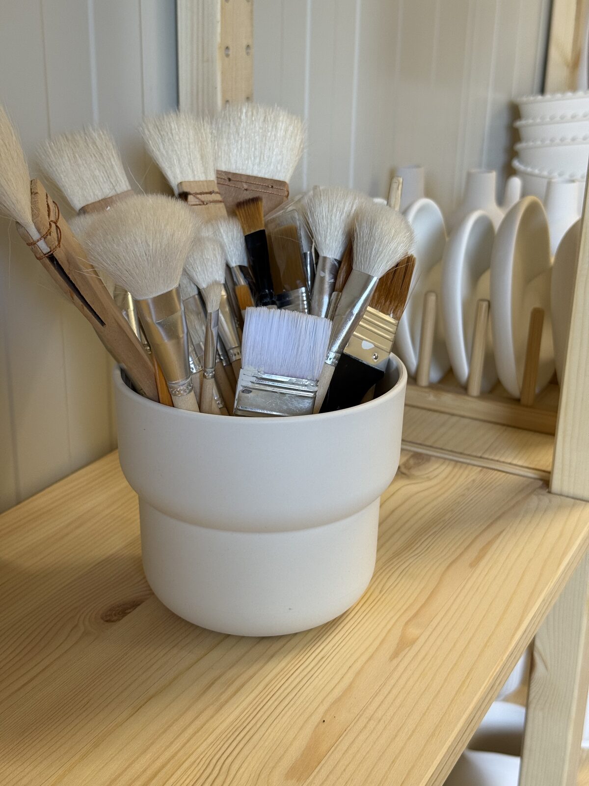 Pot met kwasten en gereedschap op de houten werktafel van het atelier